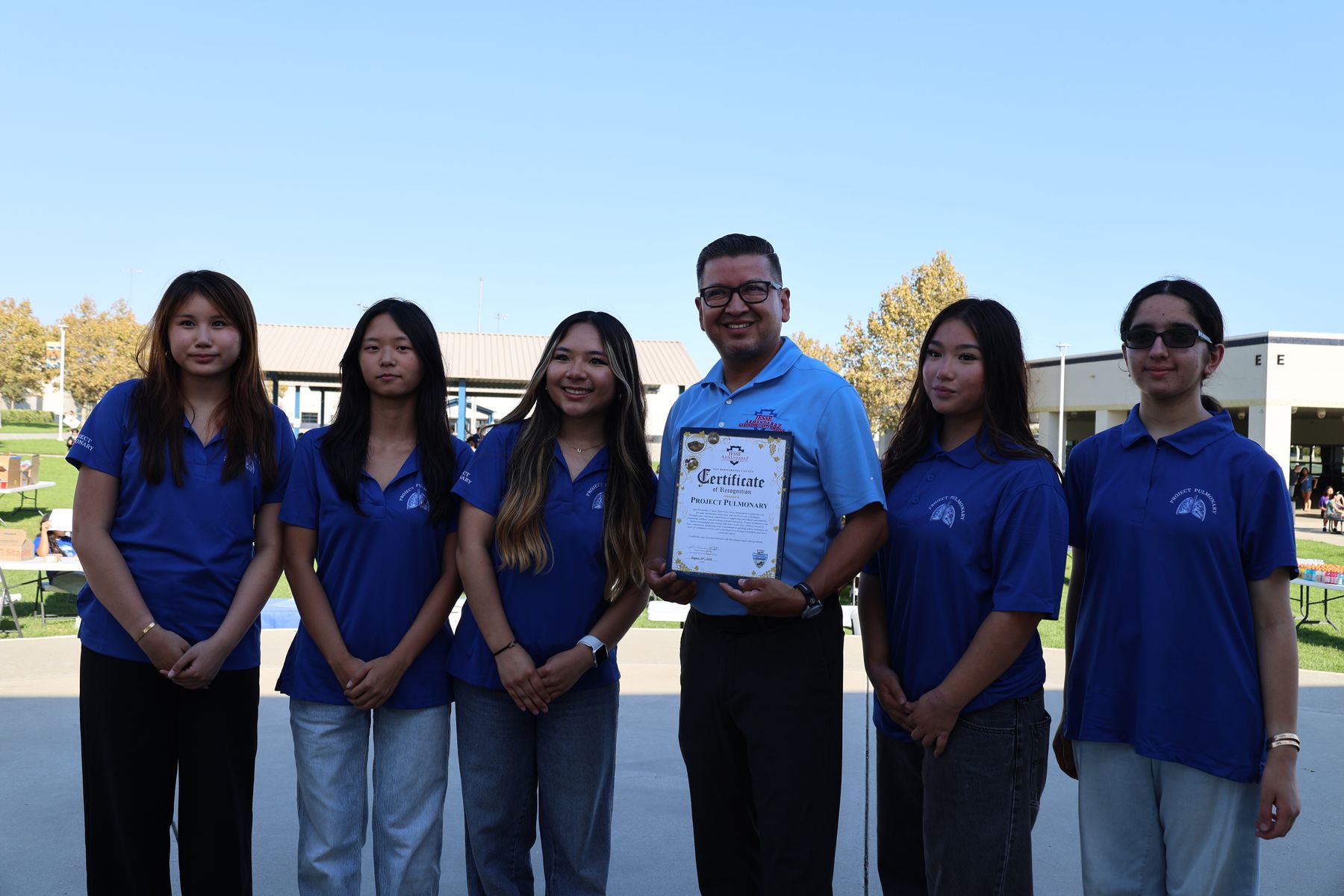 Project Pulmonary leaders with a local official holding a certificate of recognition
