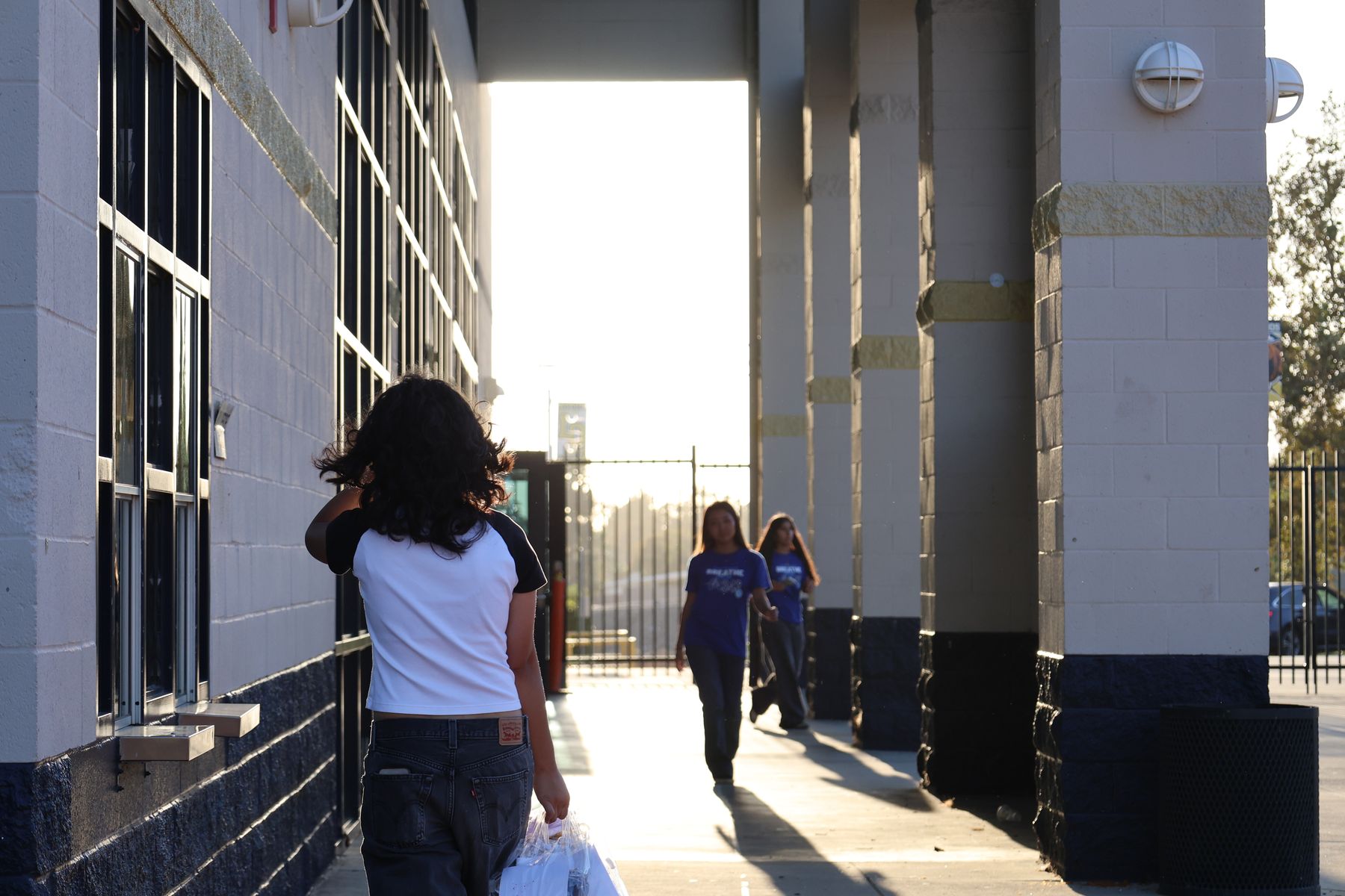 Volunteers carrying kits down a sunlit walkway