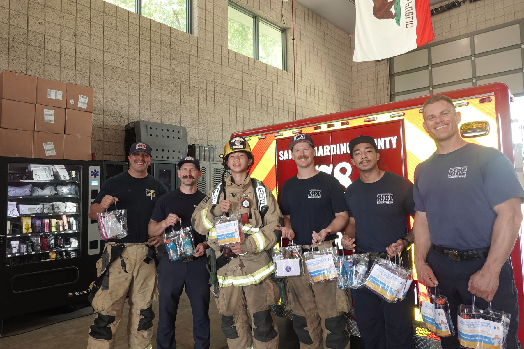 Firefighters in turnout gear holding Project Pulmonary letters and supplies