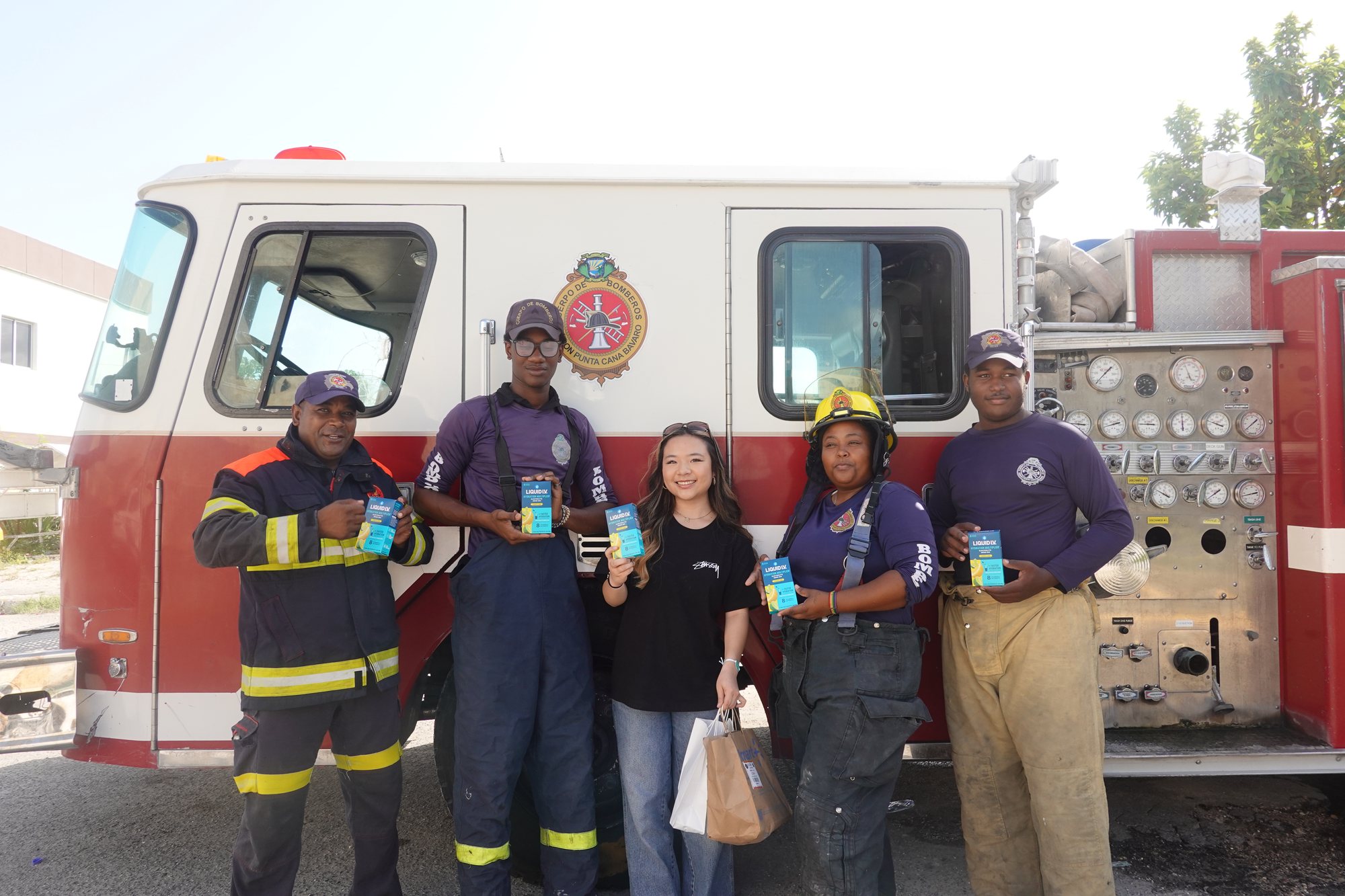 Project Pulmonary student with firefighters in the Dominican Republic holding hydration donations
