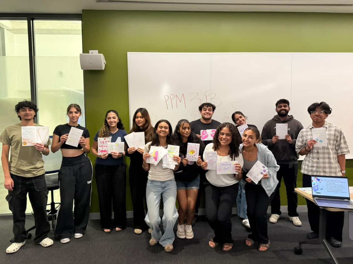 Students holding handmade get-well cards in a classroom
